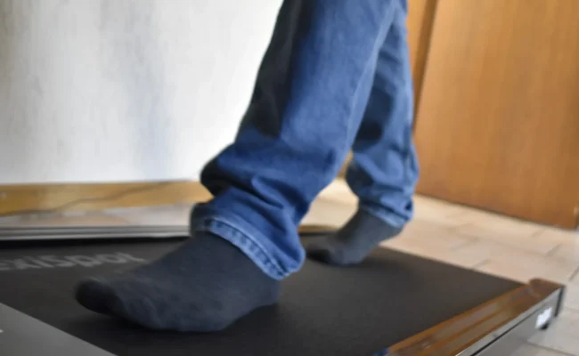 Tapis de marche sous bureau Flexispot MotionX installé sous un bureau assis-debout Flexispot E7 Pro relevé.